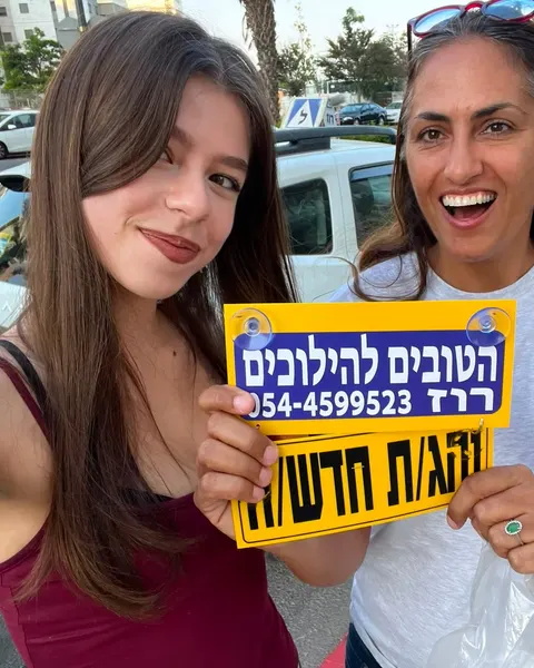 רוז ותלמידה מחייכות עם שלט נהגת חדשה